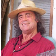 Man with long dark hair wearing a straw hat and red shirt